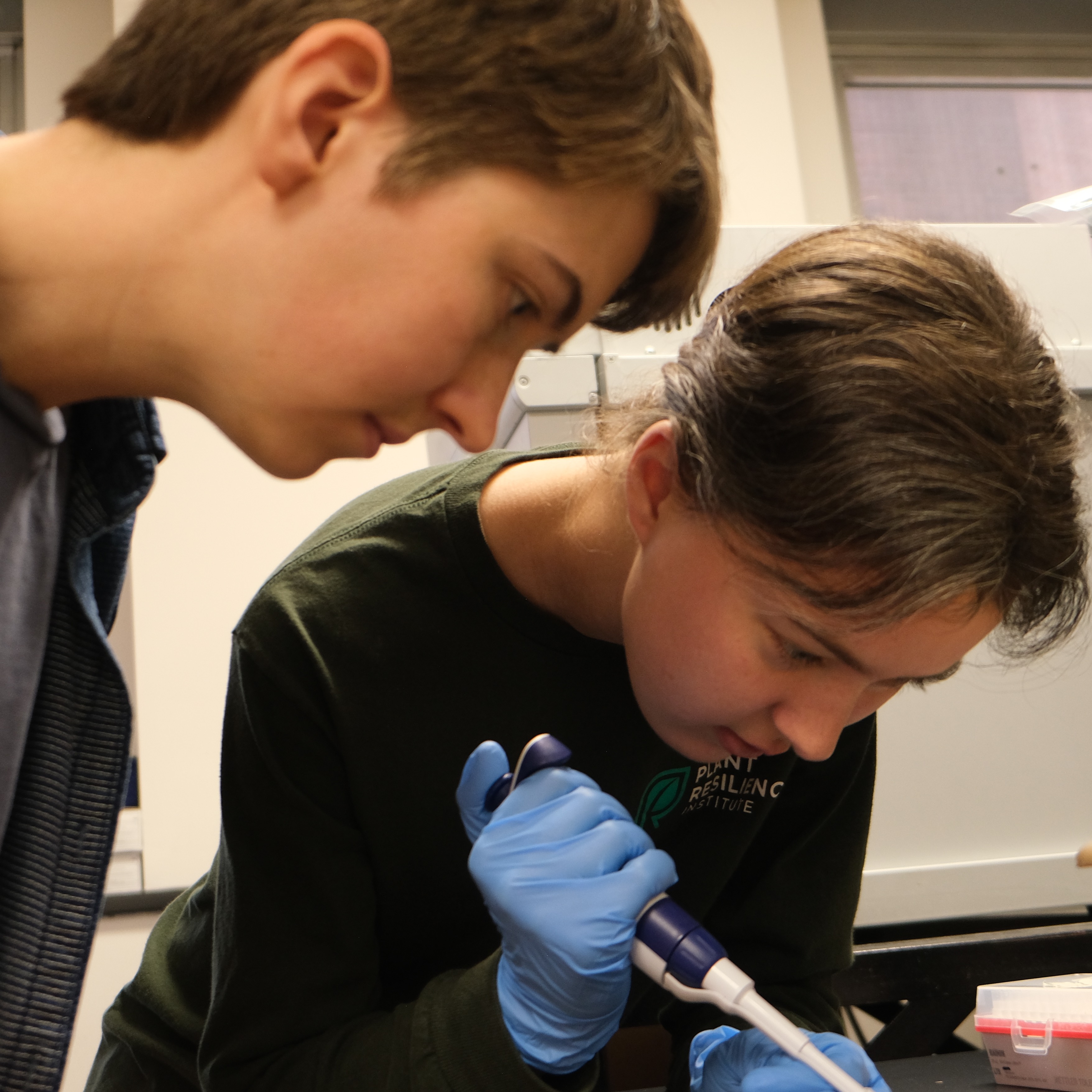 Madison and Sylvia examining a plant together in the lab